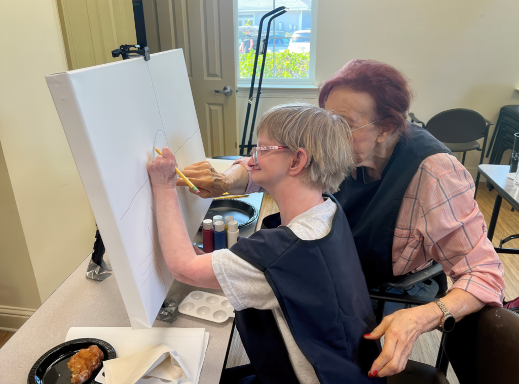 Woman helping disabled individual paint